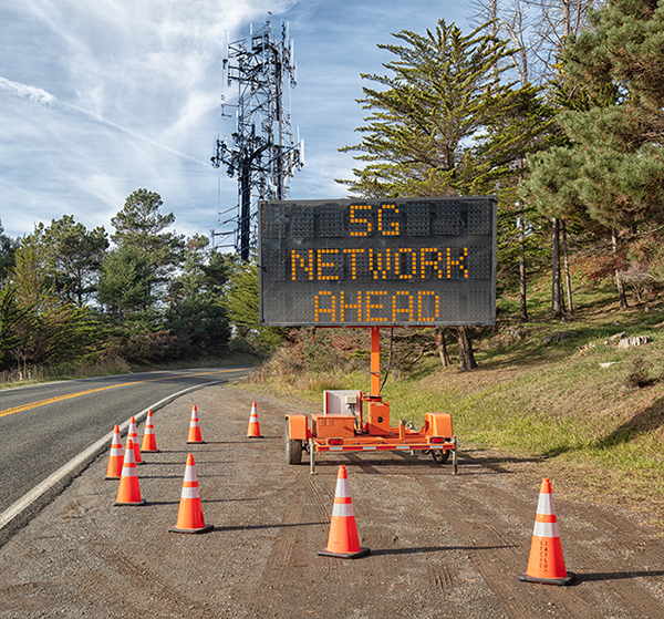 5G communications tower for mobile phone: Roadside warning sign on rural road.